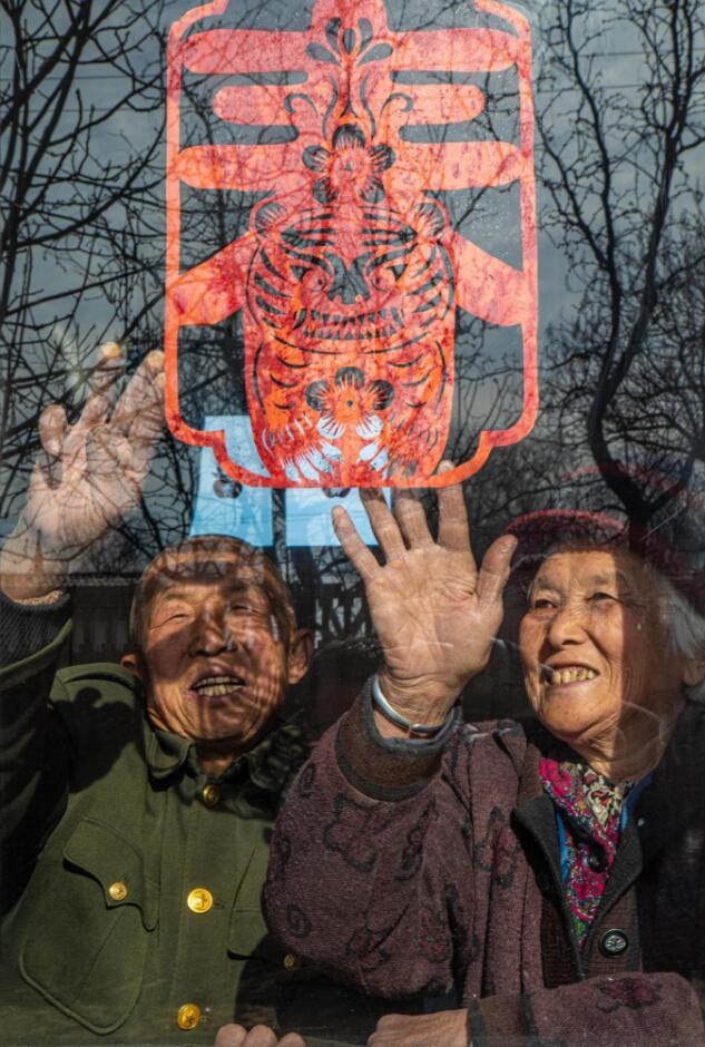 臘月里，霍州市師莊鄉(xiāng)馮南垣村村民師榮光(左)在災(zāi)后重建的新家里貼窗花。(霍州市委宣傳部供圖)