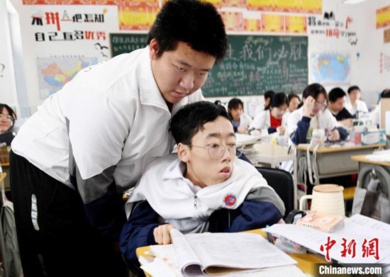朱金祥(左)把鐘華強放到課堂座位上后，都要把他擺正好，確認安全后才回到自己的座位上。 卓忠偉 攝