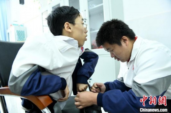 江西省南康中學(xué)北校區(qū)的高三學(xué)生朱金祥(右)正在給鐘華強(左)系好鞋帶。 卓忠偉 攝