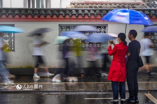 6月7日，在浙江省2023年普通高校招生考試鎮(zhèn)海中學考點，家長冒雨目送子女進入考場。人民網(wǎng) 章勇濤攝