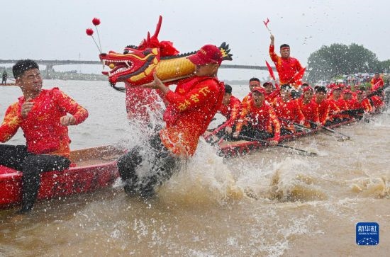 6月22日，在湖南省岳陽市湘陰縣湘江臨資口水域，參加龍舟賽的隊員接“龍頭”下水。