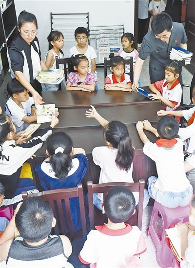  圖④：法院干警為留守兒童發(fā)放暑假讀物。