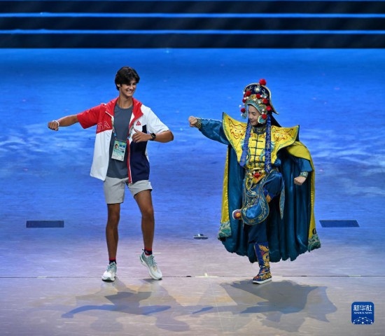 7月29日，美國運動員杜恩（左）在聯(lián)歡會現(xiàn)場與川劇演員互動。新華社記者 蔡湘鑫 攝