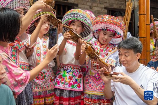 7月29日，在重慶市綦江區(qū)安穩(wěn)鎮(zhèn)，當(dāng)?shù)鼐用裨凇懊缂曳蚬?jié)”上用傳統(tǒng)習(xí)俗向游客表達(dá)祝福。新華社記者 唐奕 攝