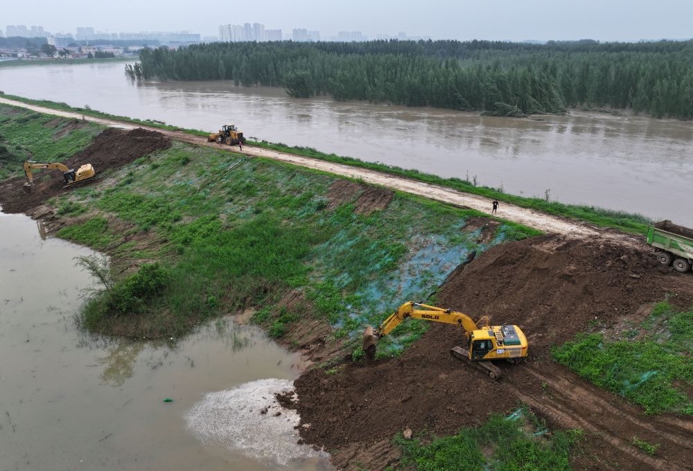 工人操作機械在白溝河左堤白溝新城高橋村段進行除險加固作業(yè)（8月4日攝，無人機照片）。新華社記者 朱旭東 攝