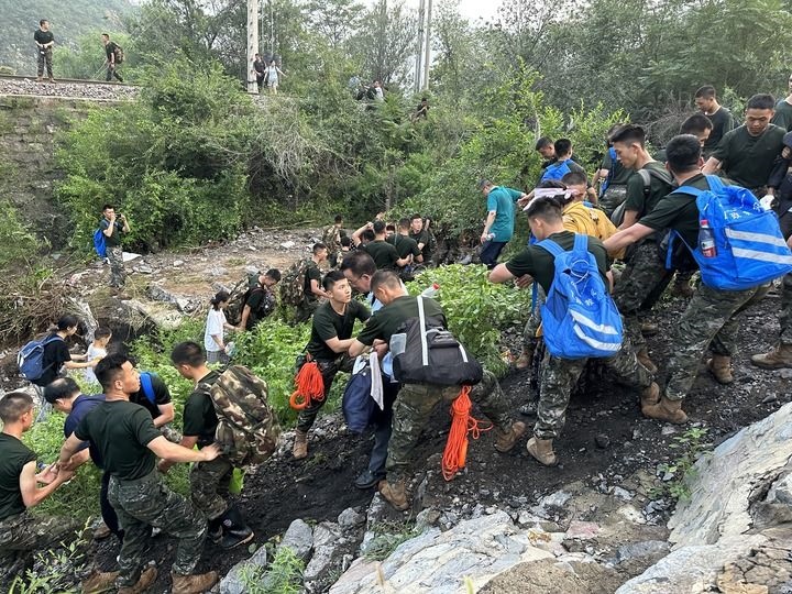 8月2日，Z180次受困列車的旅客在武警北京總隊機動第三支隊官兵的幫助下徒步前往轉(zhuǎn)運客車（手機照片）。新華社記者 王艷剛 攝
