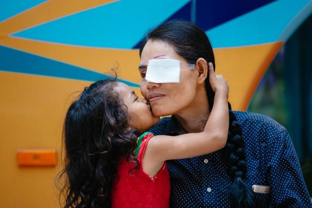 2019年3月15日，在柬埔寨磅湛省醫(yī)院，即將接受白內(nèi)障手術(shù)的患者孫美樂接受女兒的親吻祝福。在接受了中國醫(yī)療隊的白內(nèi)障義診手術(shù)后，她的視力逐步恢復(fù)，生活有了新的光明和希望。