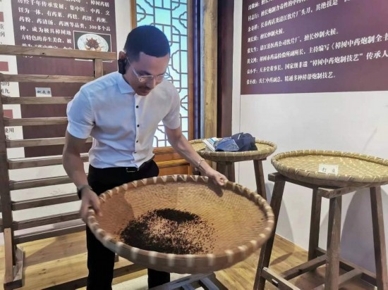 2023“一帶一路”媒體合作論壇聯(lián)合采訪團團員在非遺文化展示館體驗中藥炮制技藝。（本報記者 黃超攝）