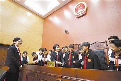 圖③：同學(xué)們穿法袍、敲法槌，爭做“小法官”。
