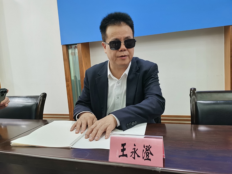 全國(guó)人大代表王永澄正在閱讀盲文版代表建議答復(fù)。本報(bào)記者 張 璁?dāng)z