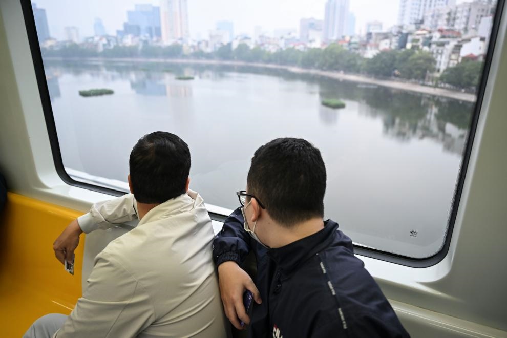 12月9日，市民在越南河內(nèi)輕軌二號線車廂內(nèi)透過車窗欣賞城市風景。