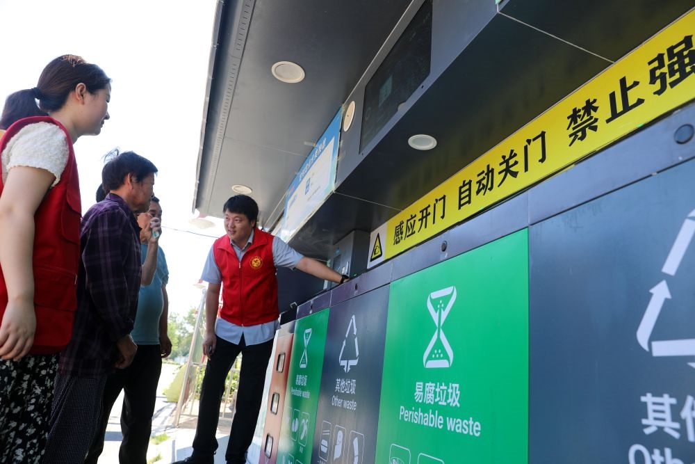在安徽省合肥市長豐縣莊墓鎮(zhèn)棗林社區(qū)，志愿者指導(dǎo)居民使用智能垃圾分類回收設(shè)備（2023年9月1日攝）。新華社記者 曹力 攝