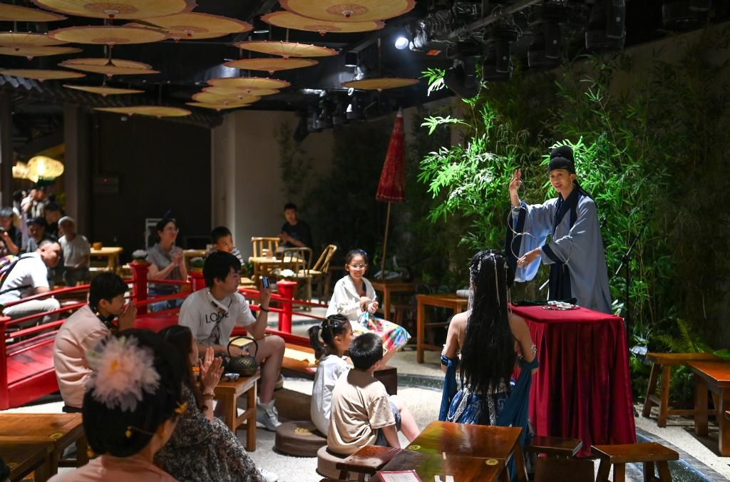 游客在長(zhǎng)安十二時(shí)辰主題街區(qū)觀看唐風(fēng)演藝《大唐曲藝》。新華社記者鄒競(jìng)一 攝