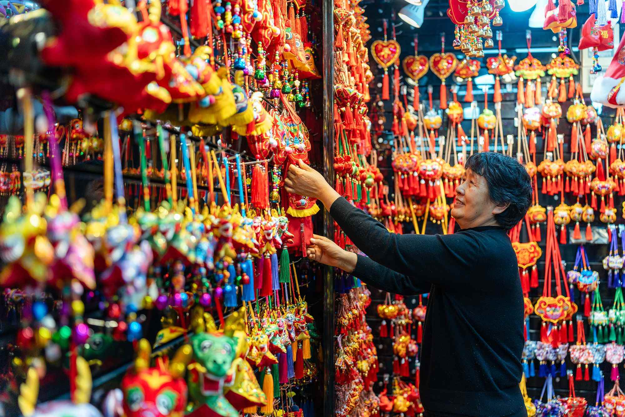 2023年12月11日，金華義烏國(guó)際商貿(mào)城，龍年喜慶用品掛滿(mǎn)攤位，顧客正在挑選中。
