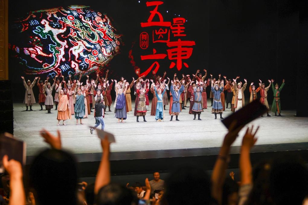 2023年7月31日，新疆和田地區(qū)新玉歌舞團(tuán)在烏魯木齊京劇院演出舞劇《五星出東方》后和觀眾互相揮手致意。這場(chǎng)演出是第六屆中國(guó)新疆國(guó)際民族舞蹈節(jié)的參演劇目之一，曾榮獲國(guó)家“文華獎(jiǎng)”等。新華社記者 郝昭 攝