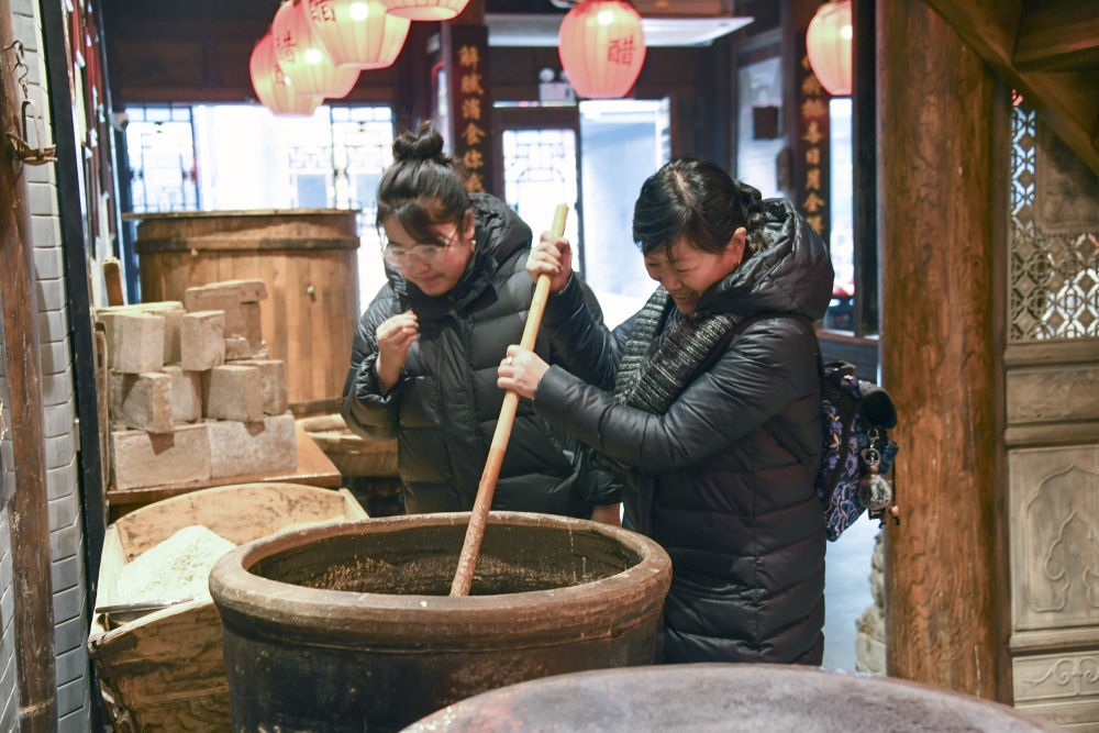游客在平遙古城東湖老醋坊內(nèi)體驗陳醋發(fā)酵打耙（2022年1月28日攝）。新華社發(fā)（梁生仁攝）