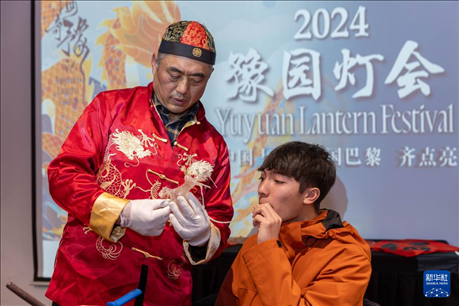 1月28日，在上海豫園舉行的民俗活動上，美國馬斯卡廷中學(xué)學(xué)生在非遺傳承人的指導(dǎo)下吹糖偶。 新華社記者 王翔 攝
