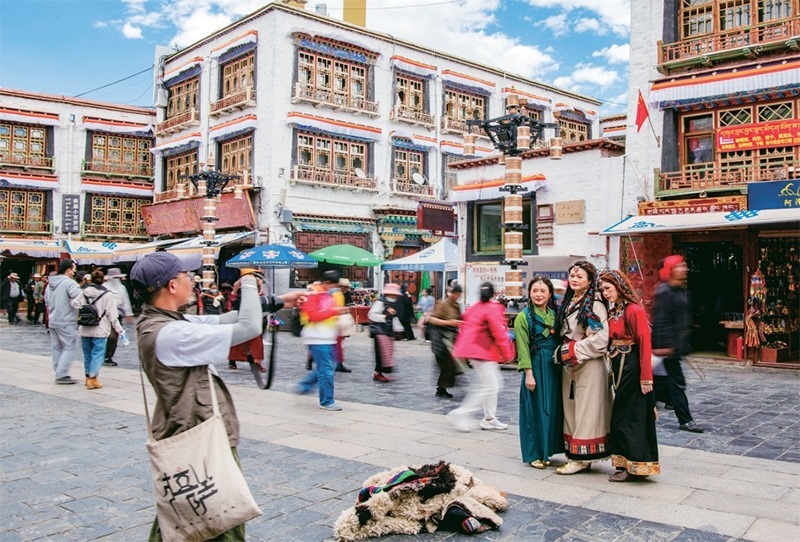 千年八廓街，見證民族團結。2021年7月，習近平總書記來到位于西藏拉薩老城區(qū)的八廓街，感慨地說：“千年八廓街，是我們各民族建起來的八廓街。各民族文化在這里交流交往交融，我們中華民族的大家庭在這里其樂融融?！眻D為2023年6月13日，游客身著藏裝在八廓街拍照留念。 新華社記者 姜帆/攝