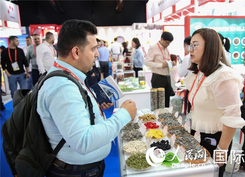圖為一家中國(guó)干果參展企業(yè)代表與采購商洽談。人民網(wǎng) 塔里克·易卜拉欣攝