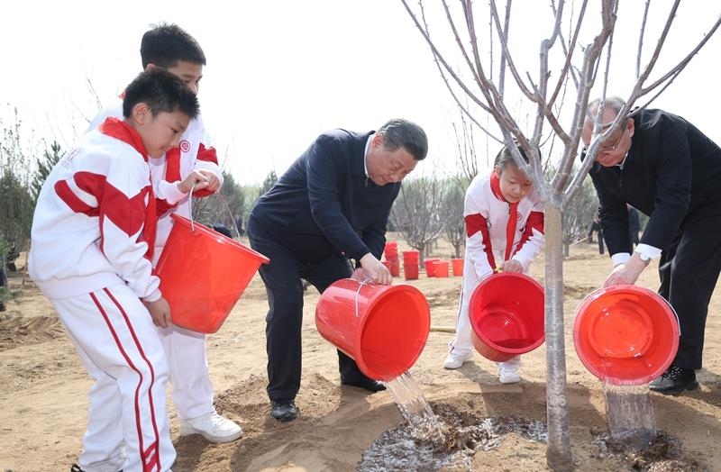2024年4月3日，習(xí)近平總書記同少先隊員一起給剛栽下的樹苗澆水。