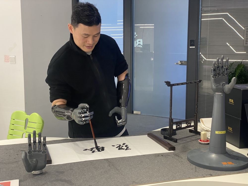 2024年3月29日，在浙江強腦科技有限公司展廳內(nèi)，失去雙手的產(chǎn)品體驗官倪敏成依靠智能仿生手寫毛筆字。新華社記者 魏一駿 攝