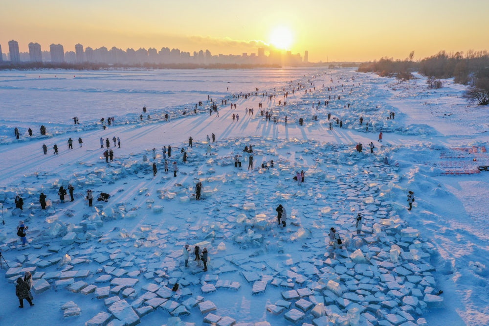 2024年1月7日，在封凍的松花江哈爾濱段，游客在日落時(shí)分的“鉆石海”游玩（無(wú)人機(jī)照片）。新華社記者 謝劍飛 攝