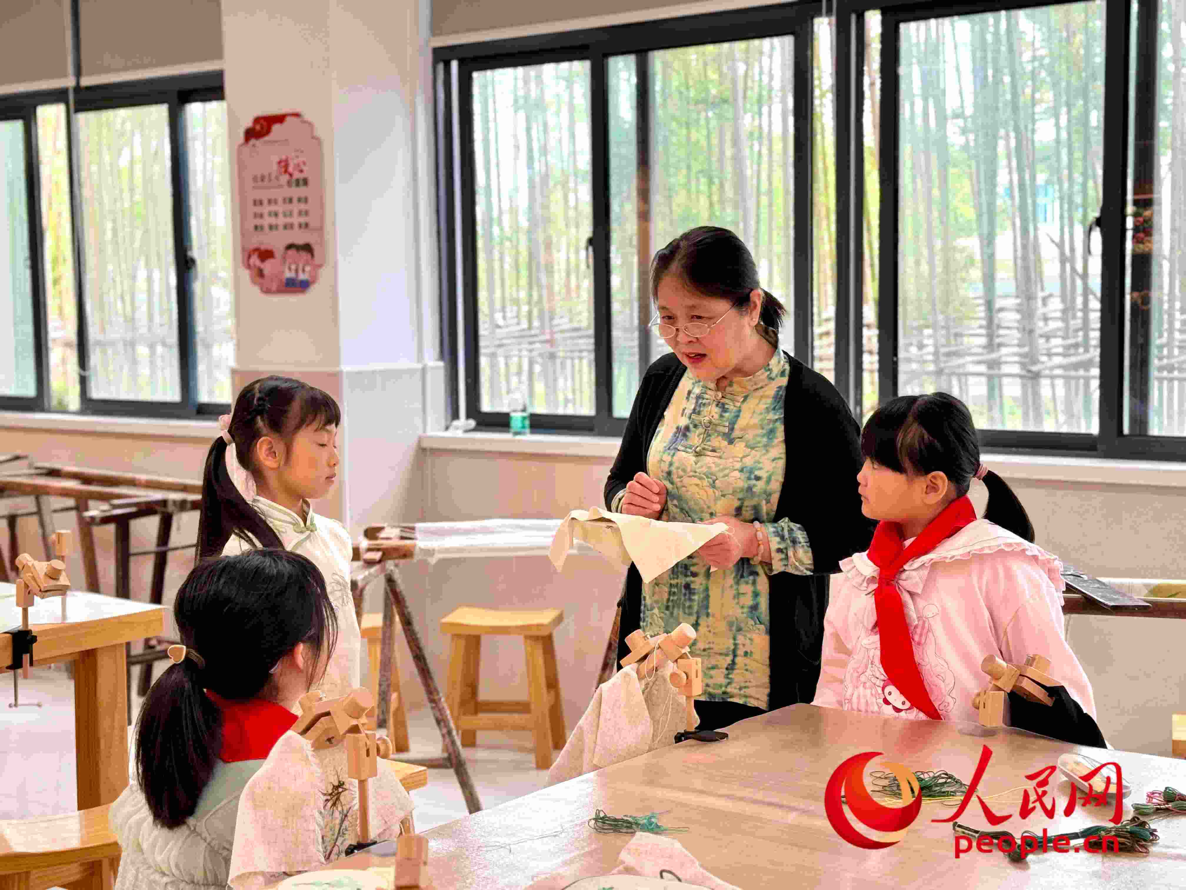 顧建珍（左三）在教孩子們刺繡知識。人民網(wǎng) 周靜圓攝