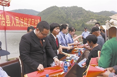 法院干警及相關部門工作人員對群眾進行生態(tài)環(huán)境保護普法教育。
