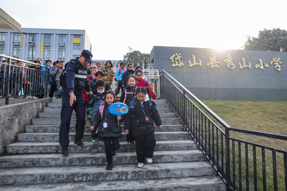 2023年12月20日，秀山派出所民警在秀山小學(xué)放學(xué)時(shí)間參與“護(hù)學(xué)崗”維持秩序，同時(shí)接獨(dú)自放學(xué)的學(xué)生去“民生小鋪”。浙江省舟山市岱山縣公安局秀山派出所聯(lián)合鄉(xiāng)鎮(zhèn)、社區(qū)成立“民生小鋪”，為當(dāng)?shù)鼐用?、外?lái)務(wù)工人員及其子女等服務(wù)，協(xié)助解決外來(lái)務(wù)工人員在工作、生活等方面的矛盾和問(wèn)題，助力鄉(xiāng)鎮(zhèn)基層治理。新華社記者 徐昱 攝