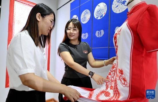 5月31日，在衡水市阜城縣一家剪紙工作室，游客在觀賞帶有剪紙?jiān)氐钠炫邸? width=