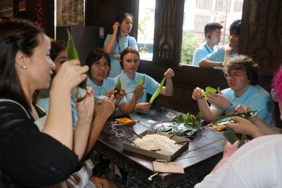 6月9日，美國青年代表在重慶永川松溉古鎮(zhèn)體驗(yàn)包粽子。新華社記者 周思宇 攝