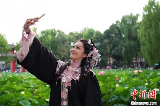 6月19日，時值一年畢業(yè)季，四川大學(xué)望江校區(qū)荷花池里的荷花盛開，成為了畢業(yè)生們的打卡圣地，吸引了眾多畢業(yè)生拍照留念。圖為畢業(yè)生在荷花池邊拍照留念。中新社記者 安源 攝