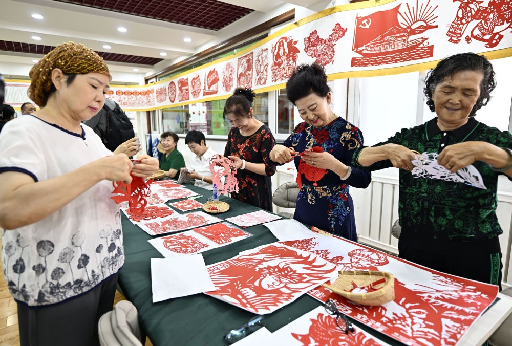6月19日，長城花園社區(qū)居民在社區(qū)“才藝堂”制作剪紙。