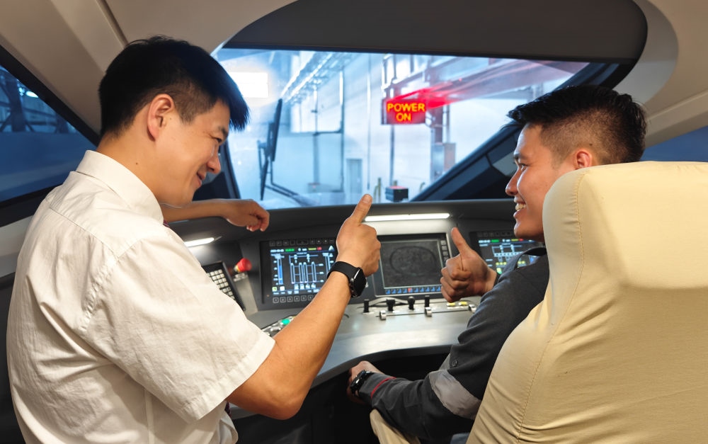 2023年8月25日，在印度尼西亞萬隆的雅萬高鐵德卡魯爾動(dòng)車所內(nèi)，中國師傅穆振（左）向印尼火車司機(jī)塞蒂亞萬講解動(dòng)車組出庫前的上電作業(yè)。新華社記者 徐欽 攝
