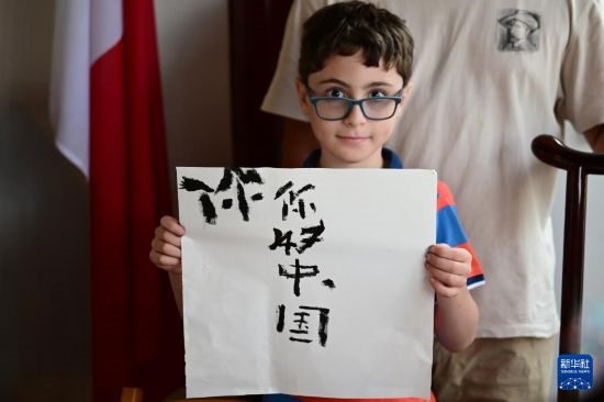 7月4日，在馬耳他桑塔露琪亞市的中國古典園林“靜園”，一名男孩展示他的書法作品。新華社發(fā)（喬納森·博格 攝）