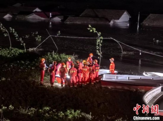  7月6日凌晨3時，在湖南岳陽華容縣團洲垸洞庭湖一線堤防，救援人員剛剛完成一次救援任務，遠處是被淹的民房。中新社記者 白祖偕 攝