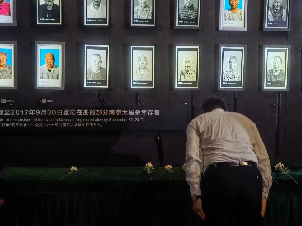 7月18日，人們向離世的南京大屠殺幸存者獻(xiàn)花、鞠躬。新華社記者邱冰清 攝