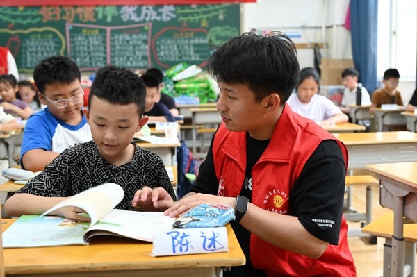 鄭州市二七區(qū)暑托班的志愿者輔導孩子寫作業(yè)。人民網(wǎng)記者王玉興攝