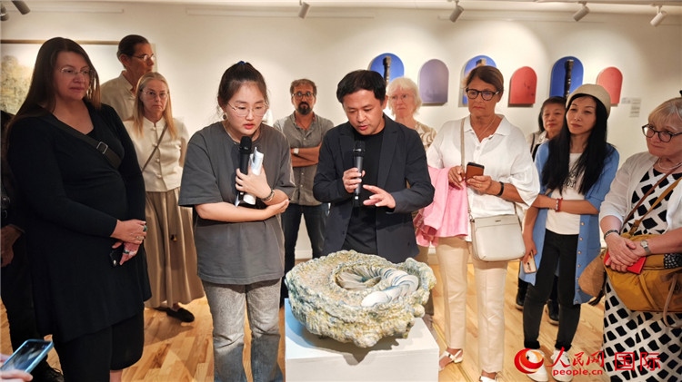 參展人、景德鎮(zhèn)陶瓷大學(xué)設(shè)計(jì)藝術(shù)學(xué)院副院長(zhǎng)余劍峰（中）向來賓介紹參展作品。人民網(wǎng)記者 殷淼攝