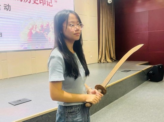 圖為南開大學(xué)社會實(shí)踐隊(duì)學(xué)生代表呼月紅在學(xué)術(shù)交流活動現(xiàn)場，展示河間調(diào)研行中獲贈的一戰(zhàn)華工蔡世春曾使用過的一把大刀。林卓瑋 攝