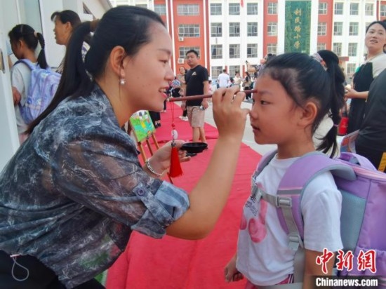 圖為衡水市利民路小學(xué)，老師為學(xué)生點朱砂痣，寓意開啟智慧。張松 攝