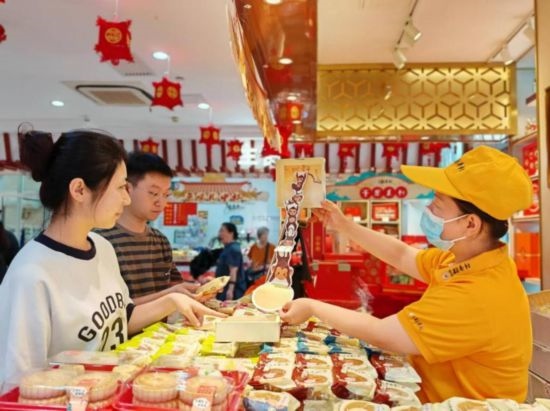 北京稻香村一家門店內(nèi)，售貨員向顧客展示新上市的月餅禮盒。（受訪者供圖）