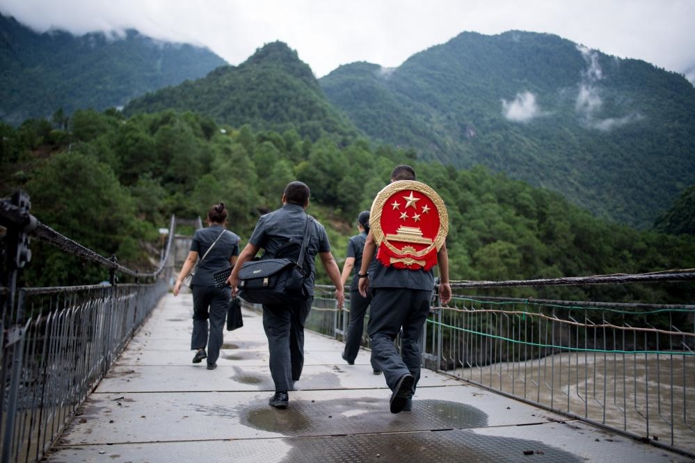 云南省怒江傈僳族自治州貢山縣人民法院法官鄧興背著國徽與同事們跨過怒江（2019年8月30日攝）。怒江高山峽谷眾多，交通不便，為方便群眾、更好地開展法律服務(wù)，背著國徽攀高山、過索橋、躲落石、鉆老林……成為鄧興法官的工作常態(tài)。新華社記者 江文耀 攝