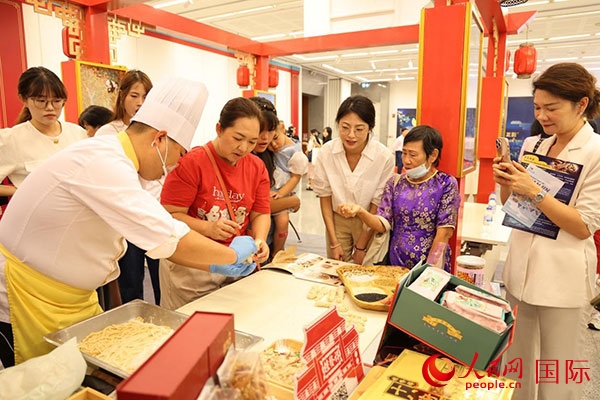 演出前，在天津桂發(fā)祥十八街麻花制作技藝非遺體驗(yàn)展臺(tái)前，泰國民眾體驗(yàn)天津麻花制作。人民網(wǎng)記者 楊一攝