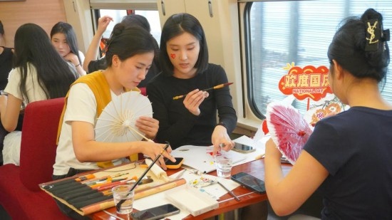10月1日，旅客們在G1634次列車上給油紙傘作畫。新華社記者周義 攝