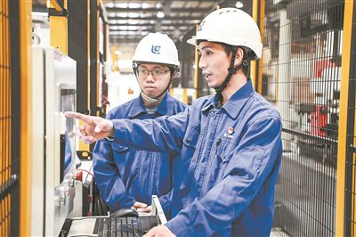 在廣西柳工機(jī)械股份有限公司生產(chǎn)車間內(nèi)，一名高級技師（右）給徒弟講解數(shù)控設(shè)備操作細(xì)節(jié)。新華社記者 曹祎銘攝