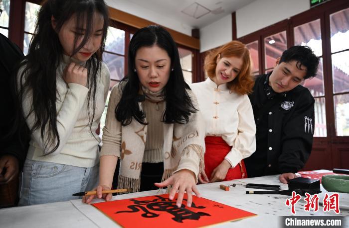 1月20日，西泠印社社員李硯（左二）為外籍留學(xué)生講述蛇年福字貼創(chuàng)作靈感。當日，來自巴西、馬來西亞、加納、哈薩克斯坦的外籍留學(xué)生在浙江杭州西泠印社體驗福貼、春聯(lián)和篆刻，感受古老的中國傳統(tǒng)文化。中新社記者 王剛 攝