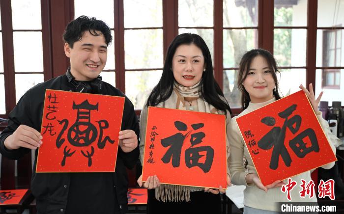 1月20日，外籍留學(xué)生和西泠印社社員李硯(中)展示各自創(chuàng)作的福貼。當日，來自巴西、馬來西亞、加納、哈薩克斯坦的外籍留學(xué)生在浙江杭州西泠印社體驗福貼、春聯(lián)和篆刻，感受古老的中國傳統(tǒng)文化。中新社記者 王剛 攝