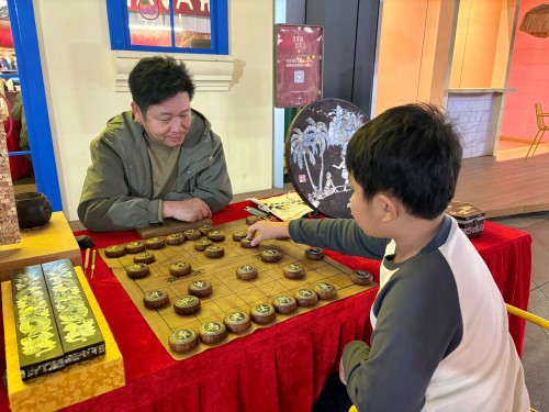 柯秋楓與市民下椰雕象棋。人民網(wǎng) 陳葉欣攝