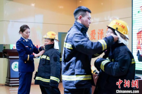 圖為學生們現(xiàn)場穿戴消防頭盔和戰(zhàn)斗服。中新社記者 趙宇航 攝
